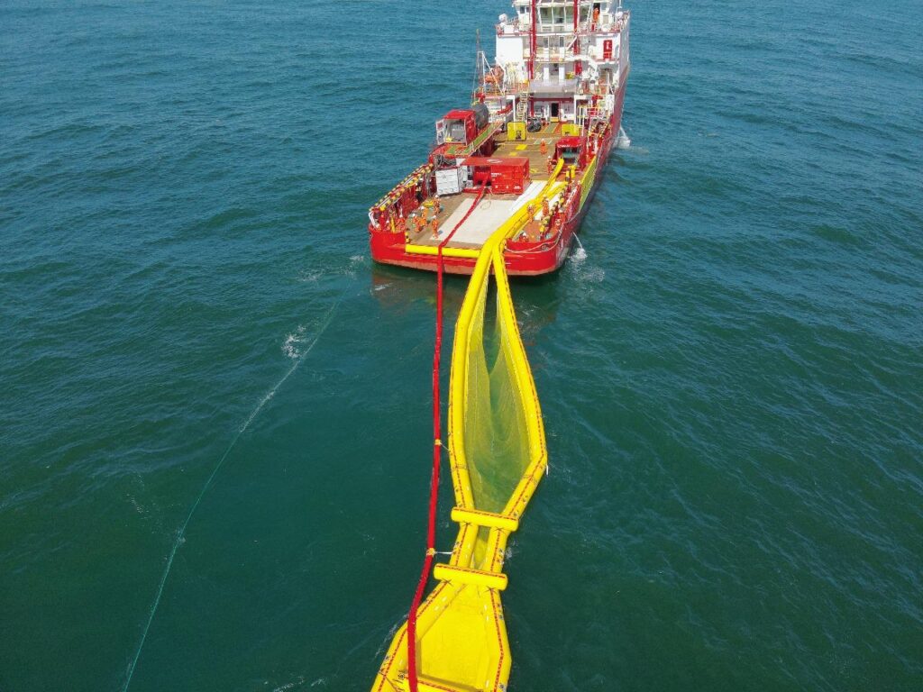 Oil spill recovery vessel deploying a containment boom at sea
